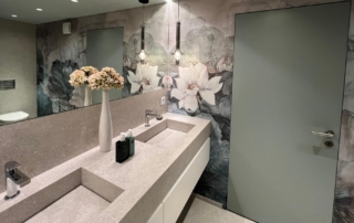 Une salle de bain avec un grand miroir et un vase avec des fleurs